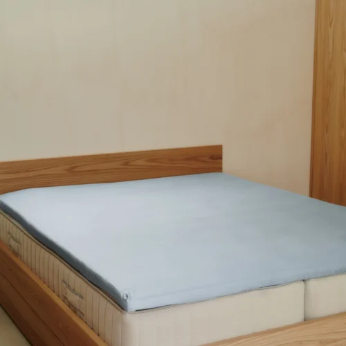 Kuvertsytt lakan i ice blue ekologisk bomull, sträckt över madrass.