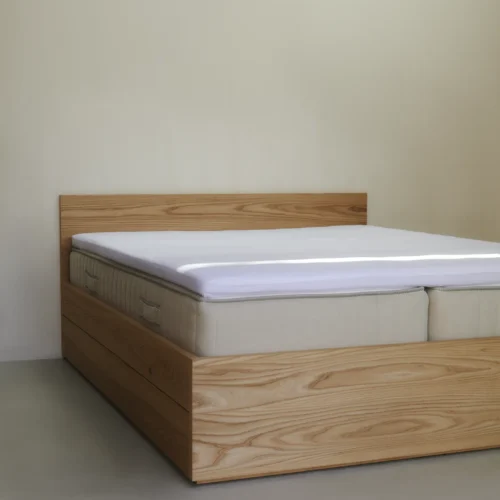 Kuvertsytt lakan i vit ekologisk bomull, sträckt över madrass.