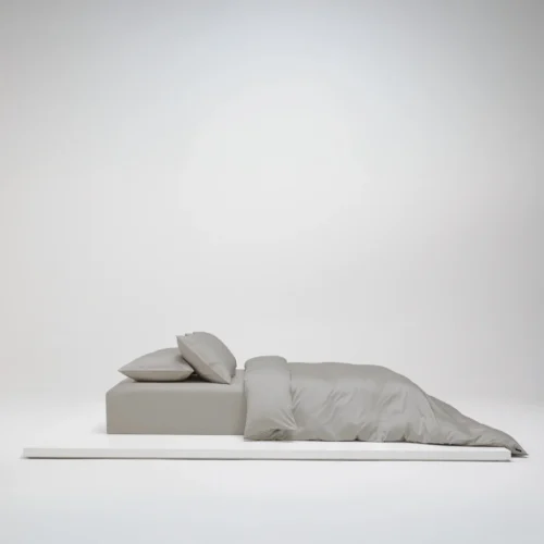 Uppbäddad säng med Shade bäddset i Modern Greige satin, tillverkat i 100 % ekologisk bomull och GOTS-certifierat.