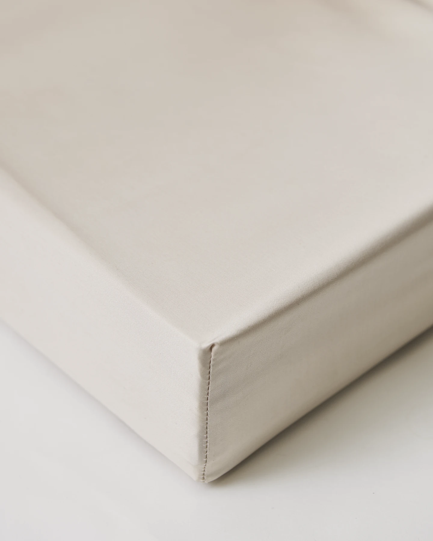 Kuvertsytt lakan i Shade satin Nordic Greige, tillverkat i 100 % ekologisk bomull. Ett elegant satinlakan i varm greige ton, utan resår, för en modern och harmonisk bäddning.